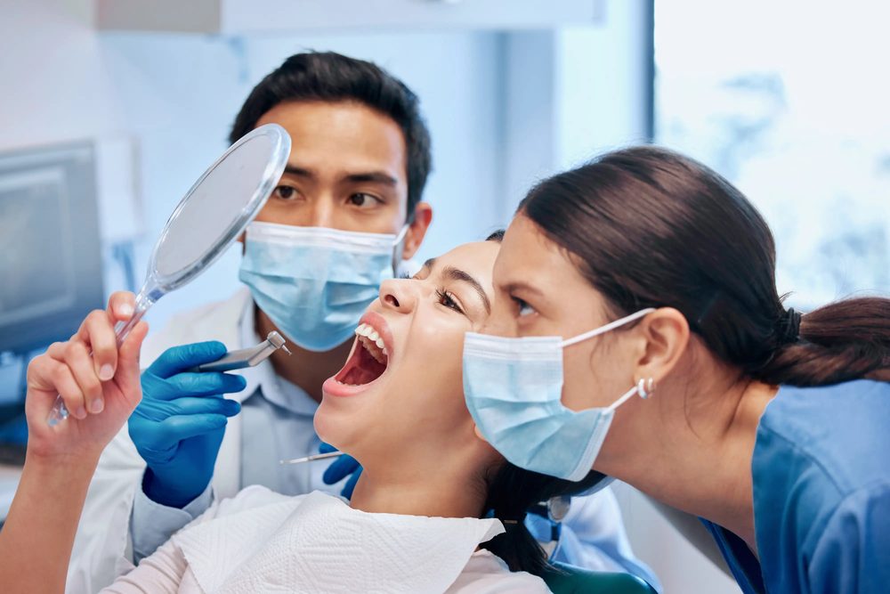 A patient holding a mirror while the dental team shows her exactly what they see